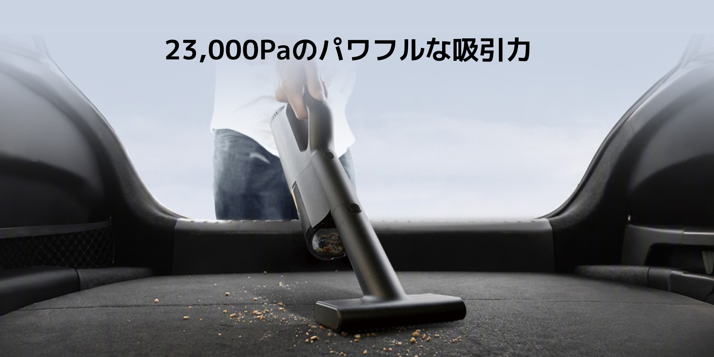 掃除機を持った人が表面を掃除しています。掃除機の吸引力は23,000Paで、地面にはいくつかの破片があります。