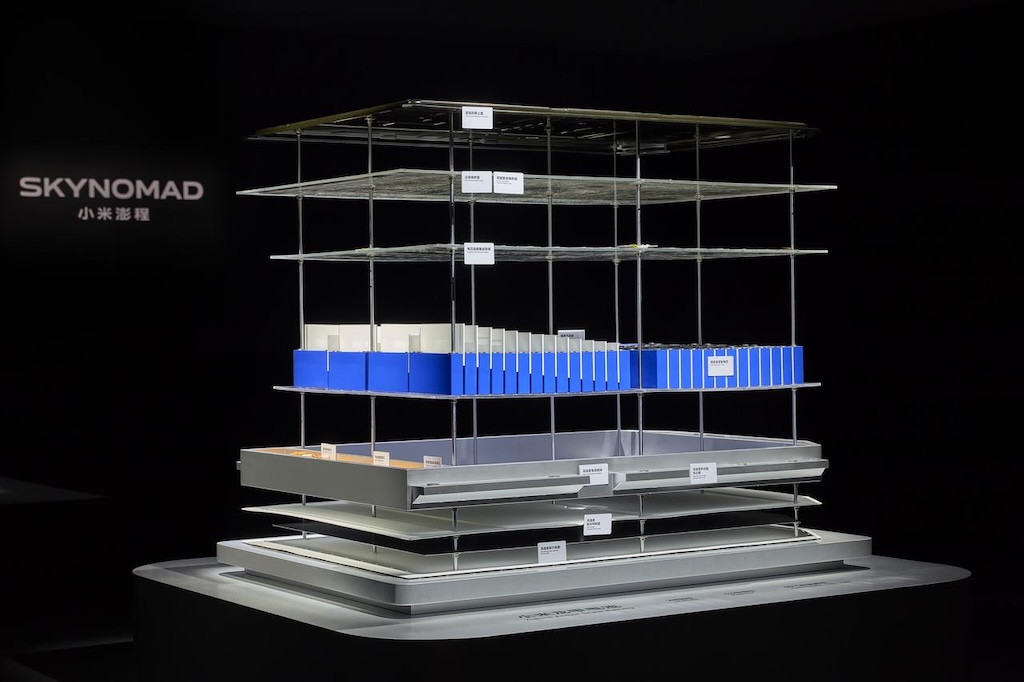 Show a model named "SKYNOMAD," with a layered structure containing several components in different colors, primarily blue and white, with a metal base and a black background.