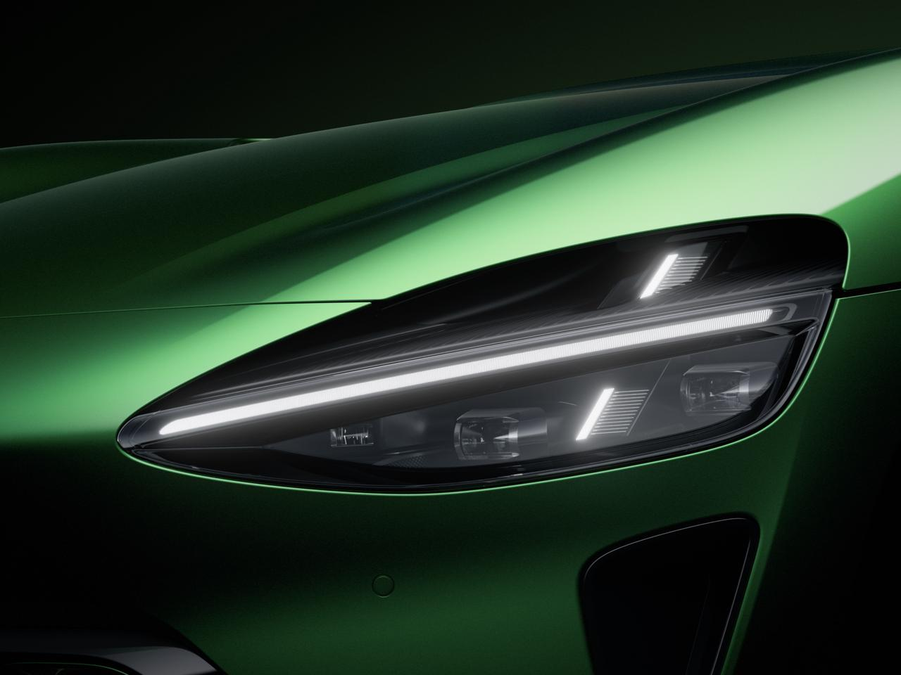 Primo piano dei fari dell'auto sportiva verde che mostra il design aerodinamico e la sensazione moderna, su uno sfondo scuro.