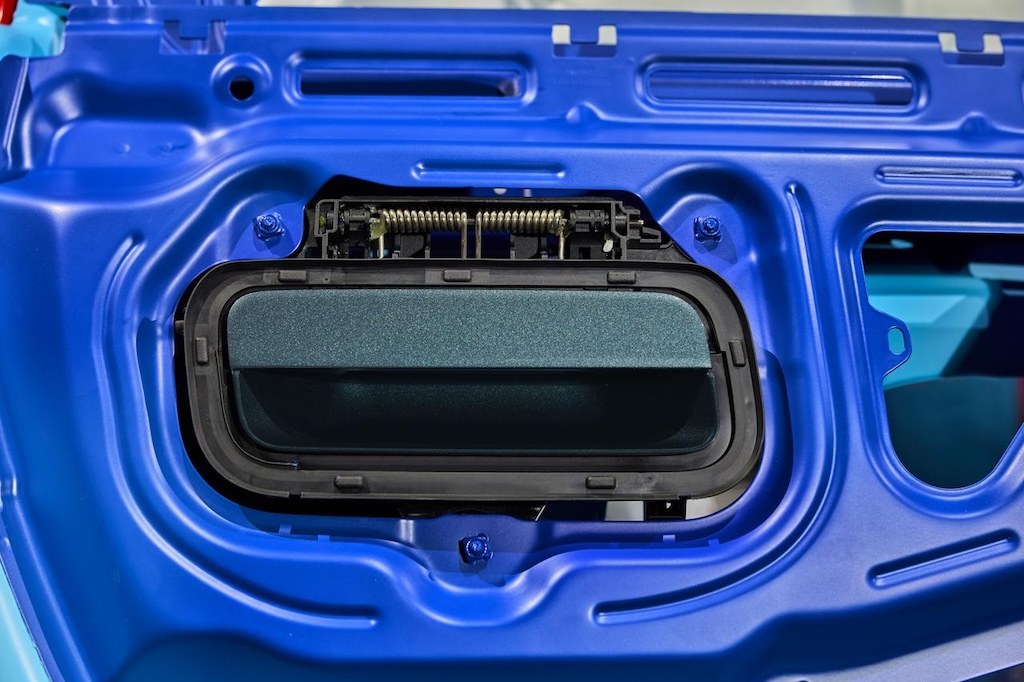 This is the internal structure of a blue car door, showing an opening that may be used for the installation of some kind of device or component. The background is a smooth blue surface, giving an overall appearance that is very neat and industrial.