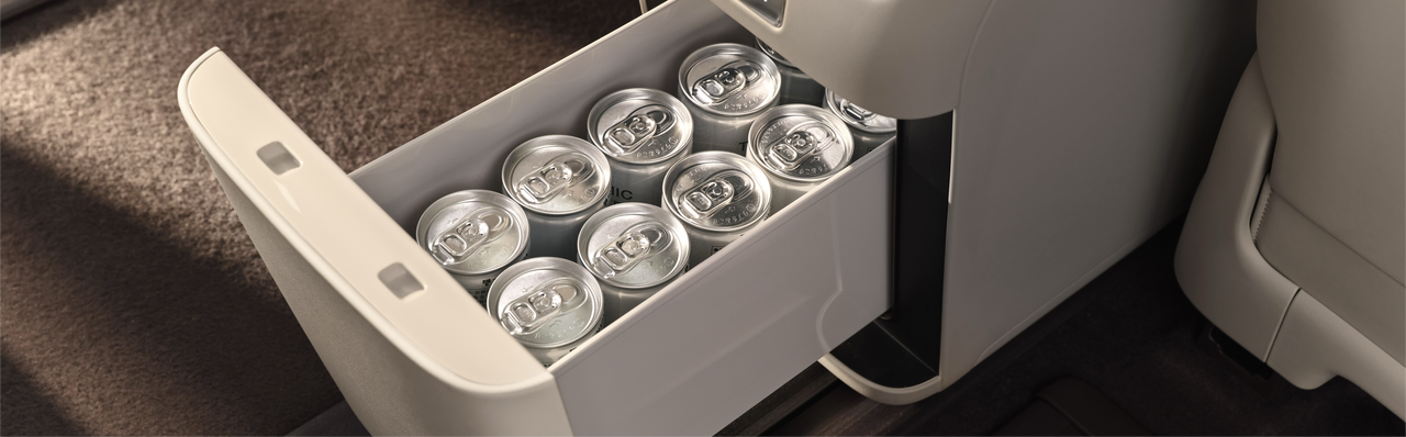 There are ten cans of beverages in the drawer inside the car, the background is the car interior, and the floor is a dark-colored carpet.