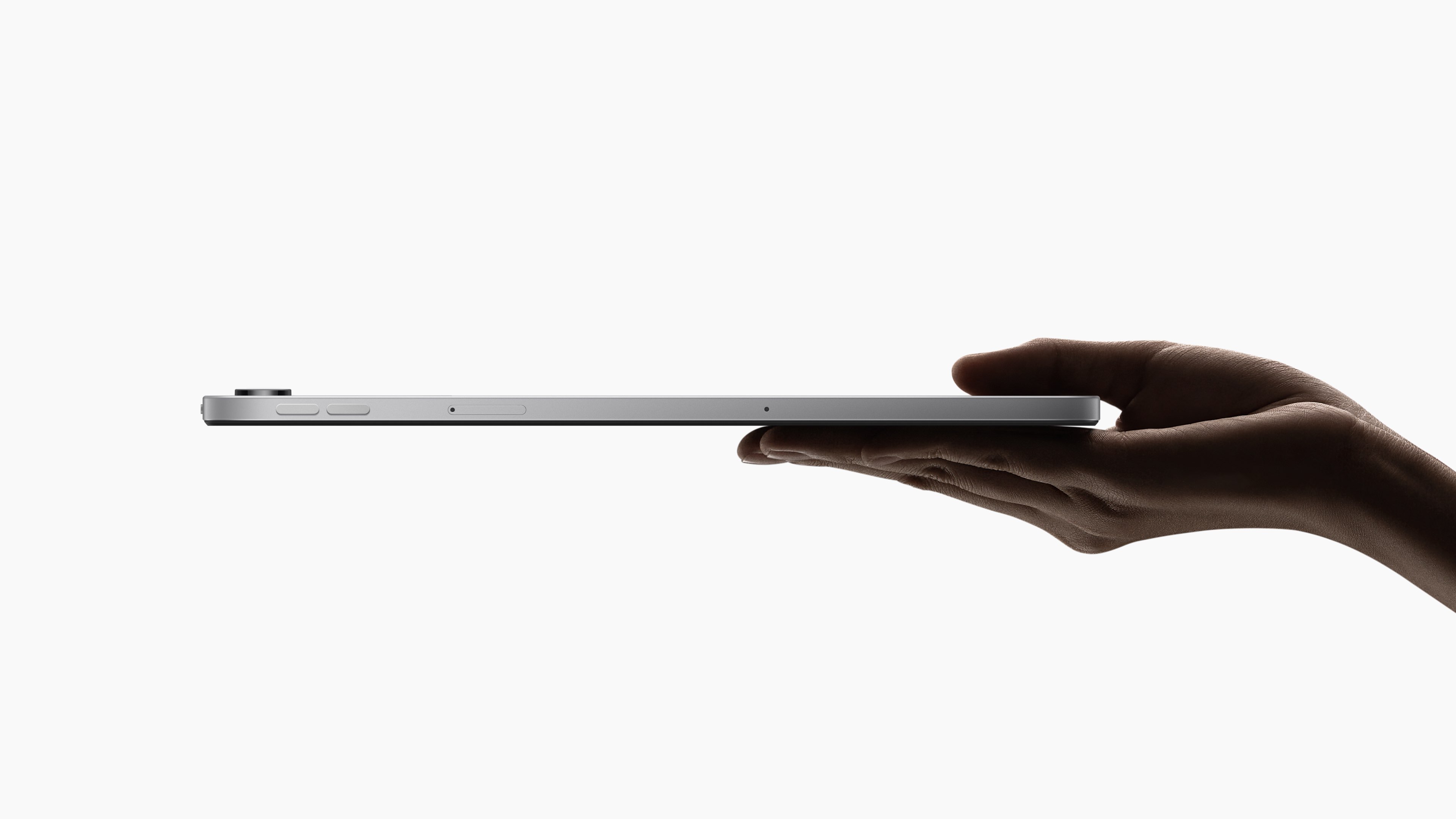 A hand is holding a tablet computer, showing its side profile. The background is pure white, highlighting the tablet's design.