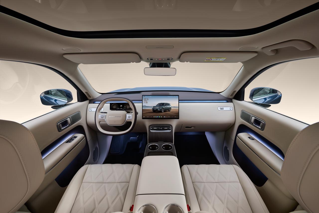 The interior perspective showcases a modern interior design featuring a digital instrument panel and a large central control screen. The seats are made of light-colored leather, and the overall style is minimalist yet high-end.