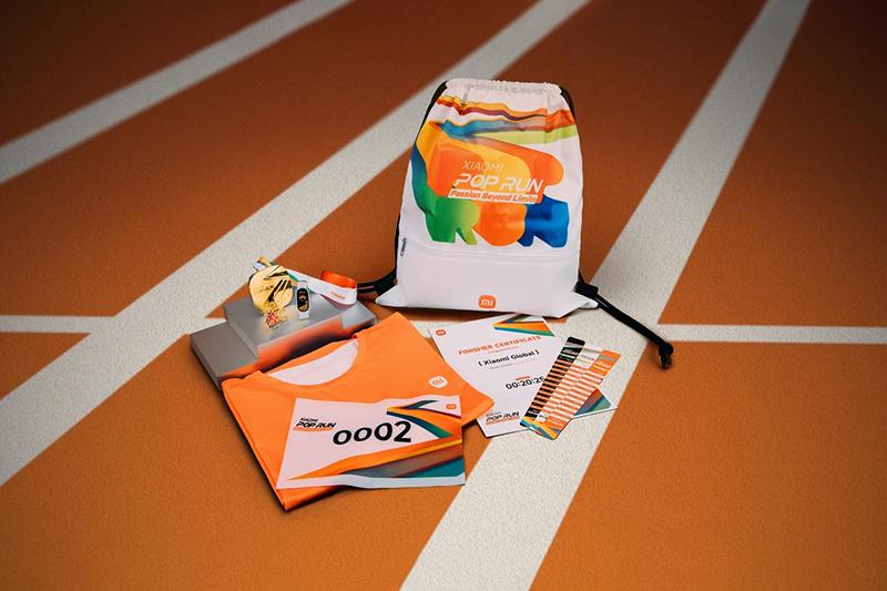The sports equipment includes an orange T-shirt, numbered 0002, accompanied by a backpack, a medal, a running wristband, and an entry ticket, with a background of a running track.