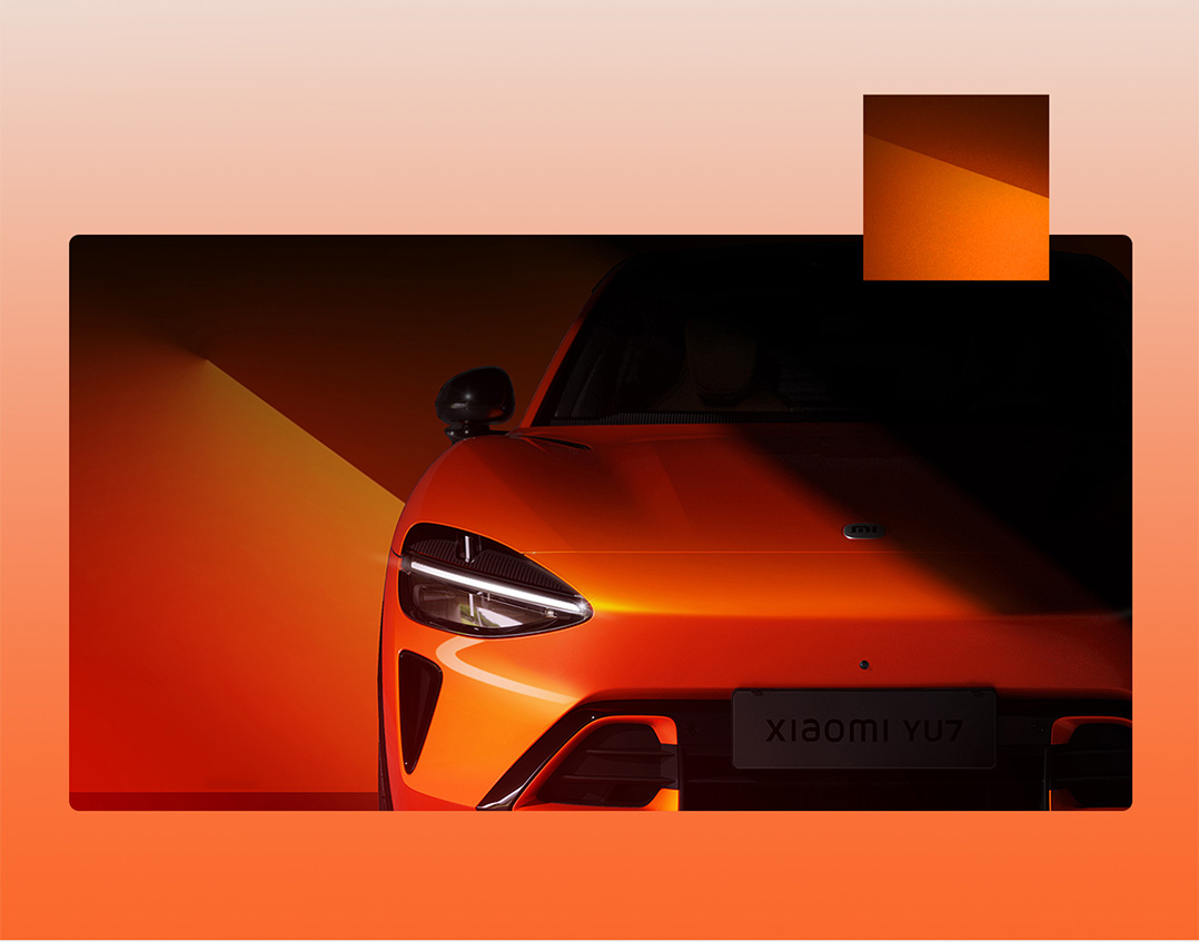 The front half of an orange sports car is illuminated by lights against a dark background, with the license plate reading "XIAOMI YU7".