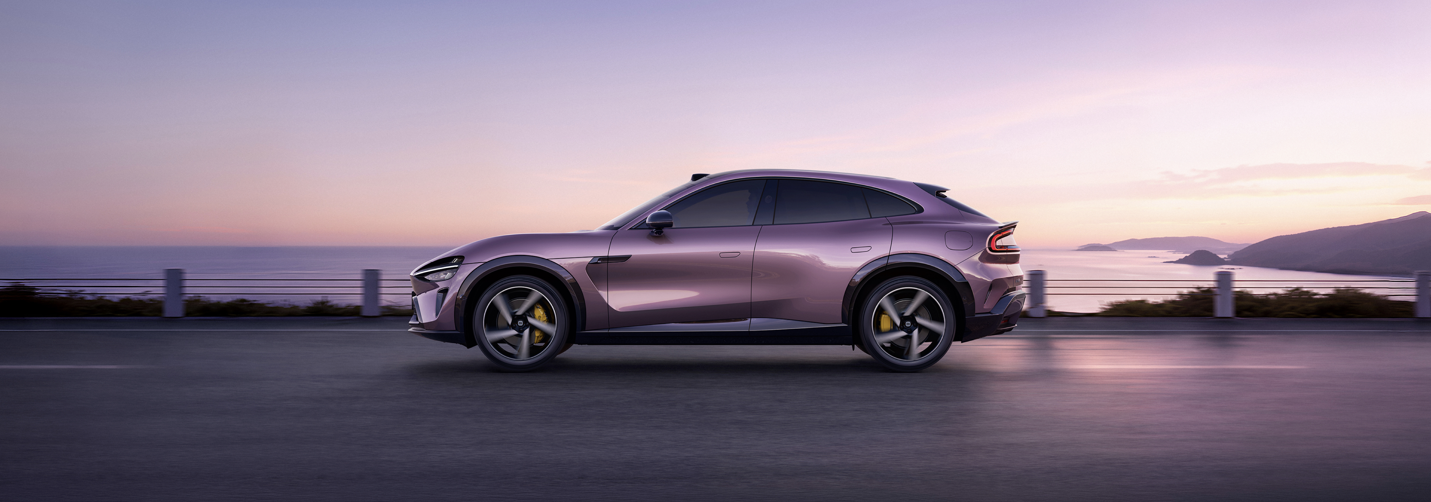A purple sports car is driving along the seaside road, with a calm ocean and a soft sunset in the background.
