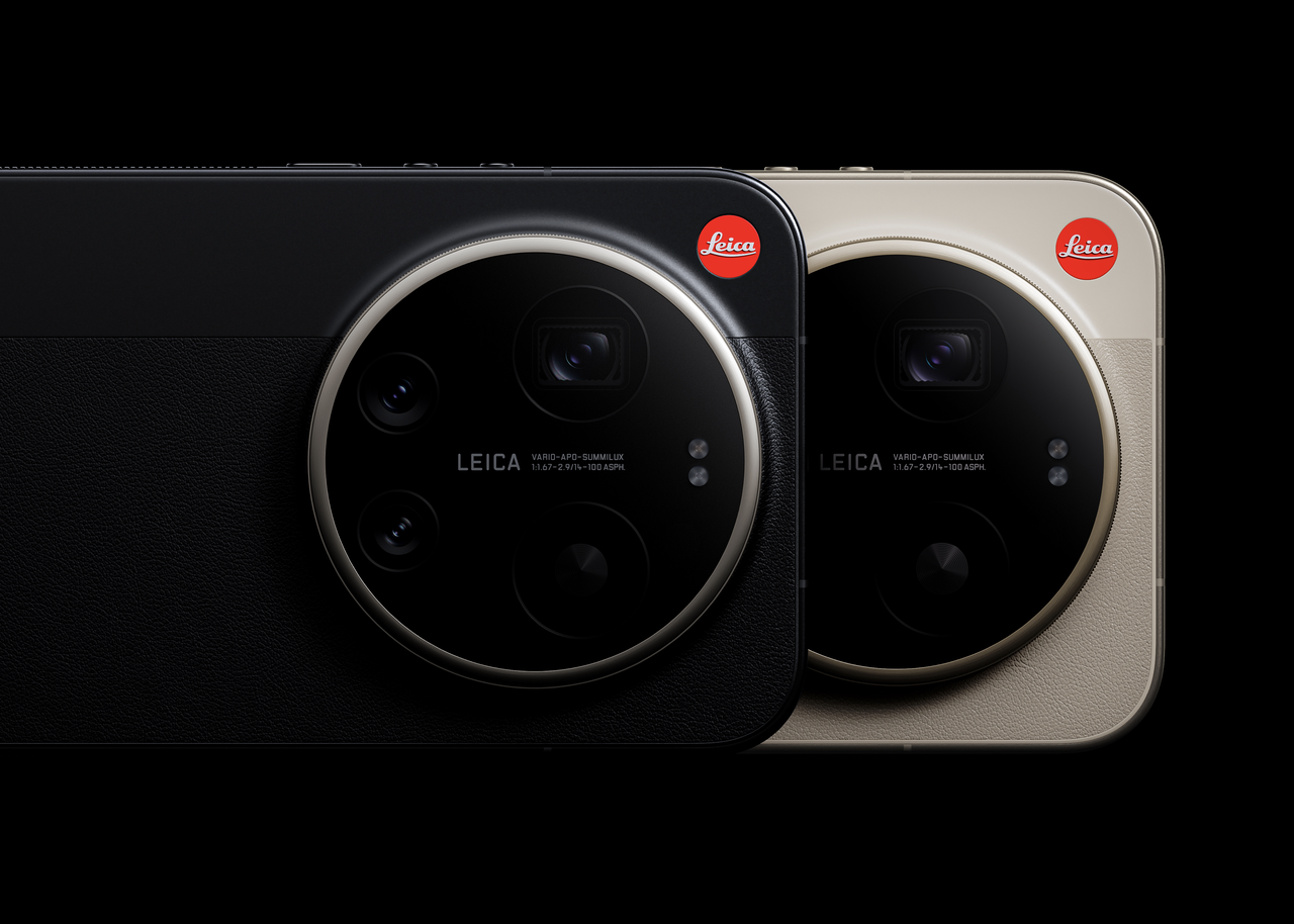 The two cameras are displayed side by side at the back, with the left one in black and the right one in beige. Both cameras are equipped with a circular lens module, which is labeled "LEICA Vario-Apo-Summilux." The background is black, highlighting the design of the devices.