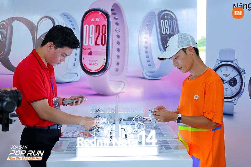 Two customers are looking at smartwatches in front of the booth, with different styles of watches in the display background and several watches placed on the table.