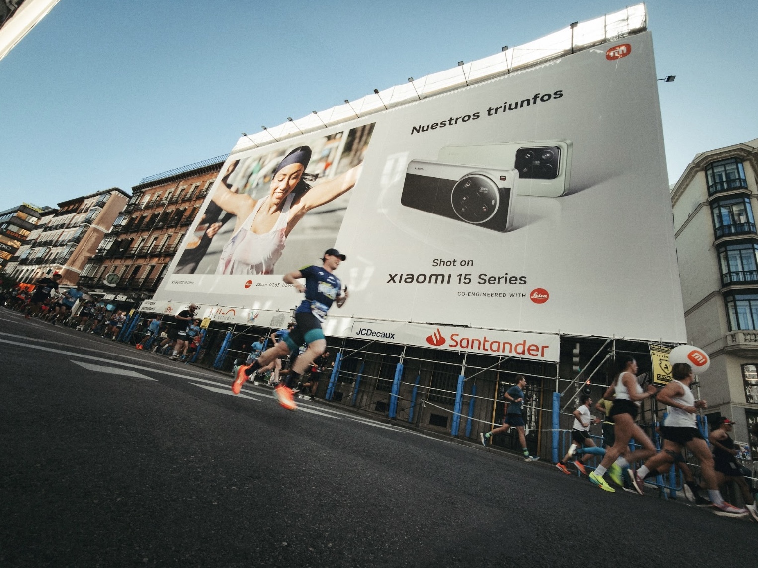 The runner is jogging on the city streets, with a large billboard in the background showcasing the Xiaomi 15 series camera, and there is a woman running on the left side.